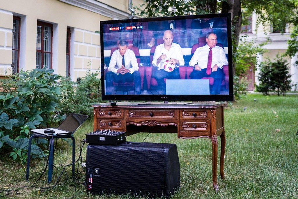 Live-Übertragung des russischen Staatsfernsehens. Die Präsidenten Macron, Infantino und Putin geben während des WM-Endspiels zwischen Frankreich und Kroatien ein harmonisches Bild ab. / Foto: Christian Frey, n-ost